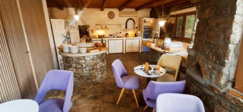 une cuisine avec des chaises violettes, une table et un comptoir dans l'établissement Mykonian Iros Suites & Villas, à Kalo Livadi