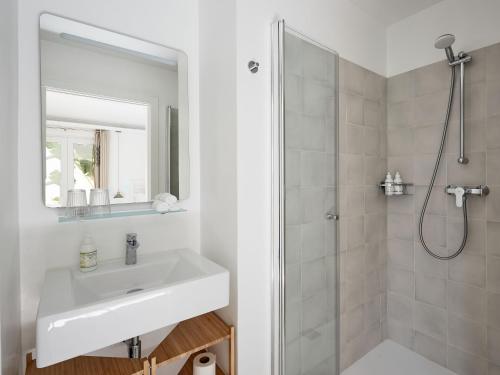 a white bathroom with a sink and a shower at Casa Apollo Guesthouse in Faro