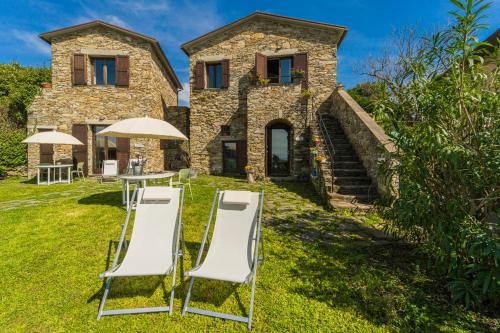 an external view of a house with chairs and an umbrella at Casale In Vigna, CinqueTerreCoast in Casarza Ligure