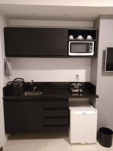 a kitchen with a sink and a microwave at Flat decorado em localização excelente in Feira de Santana