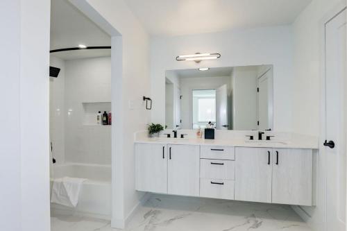 a white bathroom with two sinks and a shower at Urban Charm: 2BR Modern Retreat Close to Downtown in Arlington
