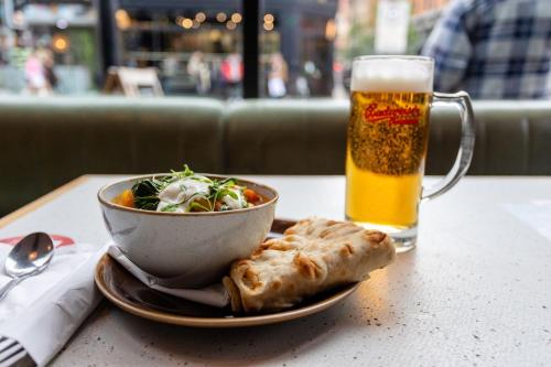 a bowl of food and a bowl of salad and a glass of beer at PH Hostel Manchester NQ1 in Manchester