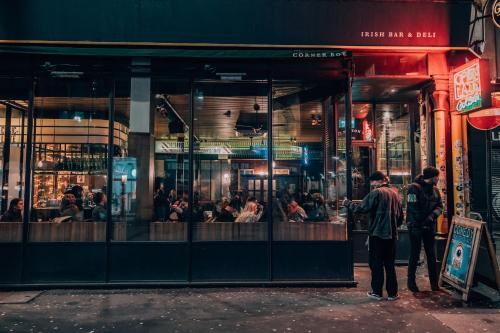 a group of people standing outside a restaurant at night at PH Hostel Manchester NQ1 in Manchester