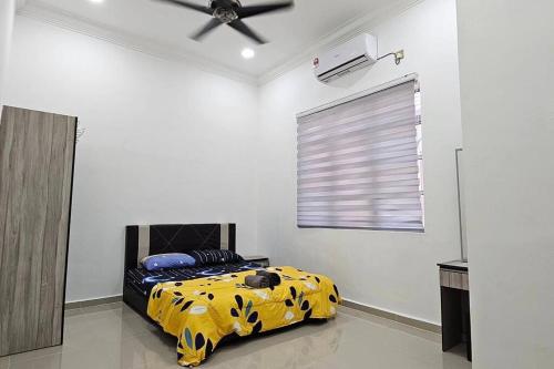a bedroom with a bed with a black and yellow blanket at Hanna Homestay with 3 Rooms in Kampong Nibong