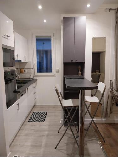 une cuisine avec une table et quelques placards blancs dans l'établissement Appartement cosy dans le marais, à Paris