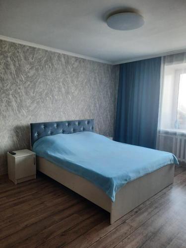 1 dormitorio con cama con sábanas azules y ventana en Сдам 1-комн квартиру в Центре, en Semey