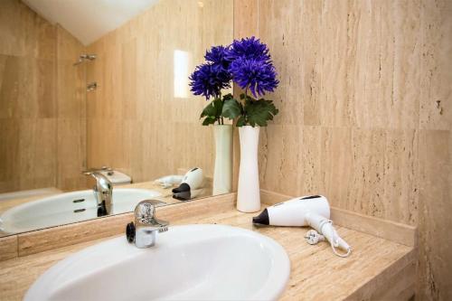 a bathroom with a sink and a vase with purple flowers at Ruim Penthouse Elviria Marbella met groot terras in Marbella