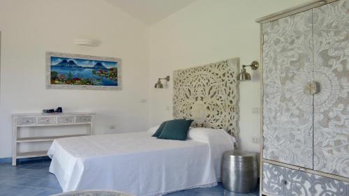 a white bedroom with a bed and a dresser at Macciuneddu Country Retreat in Golfo Aranci