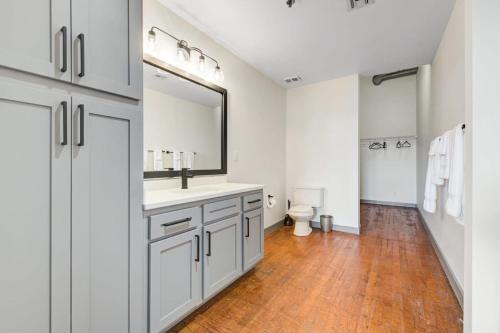 a bathroom with a sink and a toilet and a mirror at 2BR 2BA Spacious Historic Loft With Gym by ENVITAE in Kansas City