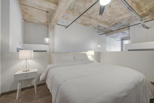 a white bedroom with a large bed and a lamp at 2BR 2BA Spacious Historic Loft With Gym by ENVITAE in Kansas City