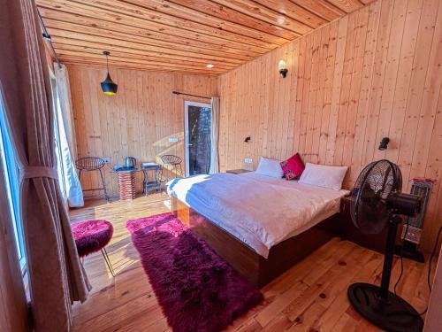 a bedroom with a bed in a wooden room at THEHIMALAYANLIVING WHISTLING PINES in Mukteswar