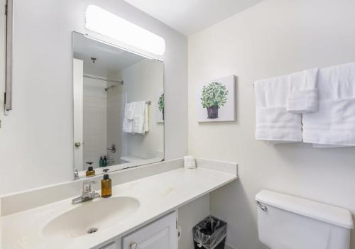 a white bathroom with a sink and a mirror at 2BR Executive Apartment with Balcony in Arlington