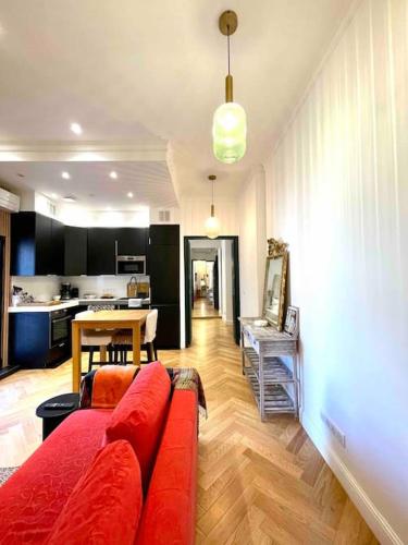 un salon avec un canapé rouge et une cuisine dans l'établissement Superbe T2 cocon en hyper centre-ville d'Ajaccio, à Ajaccio