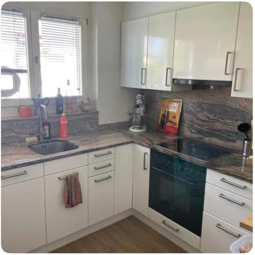 a kitchen with white cabinets and a sink at Appartment 15min from Zürich by train at the Lake in Oberrieden