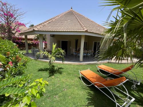 two lounge chairs and a house with a patio at Agence Adjana Resort in Saly Portudal