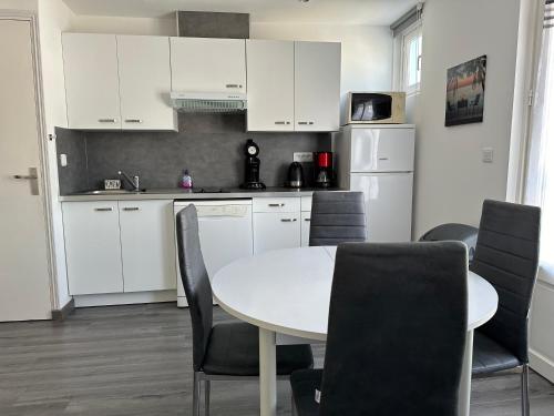 une cuisine avec des armoires blanches et une table et des chaises dans l'établissement Atlantique, à Fort-Mahon-Plage