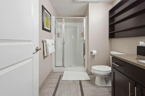 a white bathroom with a shower and a toilet at 2BR Downtown Luxury Getaway in Detroit