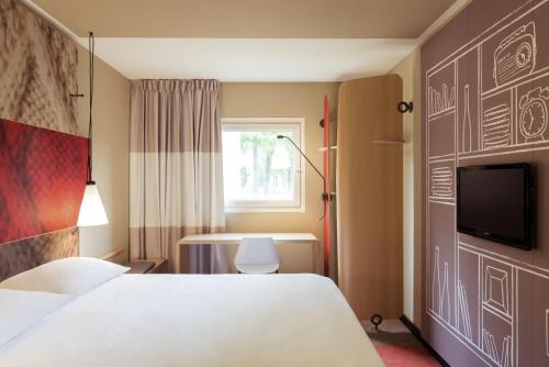 a hotel room with a bed and a tv at ibis Paris La Defense Courbevoie in Courbevoie