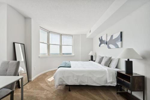 ein weißes Schlafzimmer mit einem Bett und einem Stuhl in der Unterkunft 2BR Executive City Suite With Gym & Pool in Arlington