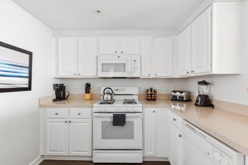 a kitchen with white cabinets and a white stove top oven at 2BR Luxury City Suite With Gym & Pool in Arlington