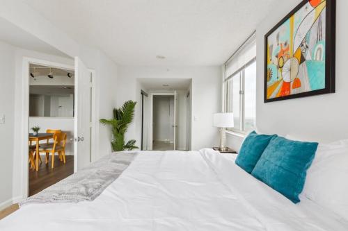 a white bedroom with a large white bed with blue pillows at 2BR Luxury City Suite With Gym & Pool in Arlington