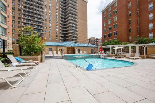 an outdoor swimming pool with chairs and a swing at 2BR Luxury City Suite With Gym & Pool in Arlington