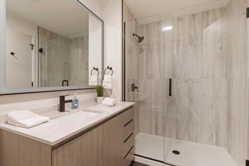 a bathroom with a shower and a sink and a mirror at 2BR Chic New Apartment With Rooftop Pool & Gym in Chicago