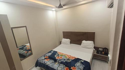 een kleine slaapkamer met een bed en een spiegel bij Goroomgo BNK Grand Varanasi - Ganga River 100m in Varanasi