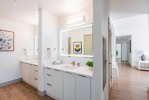 een witte badkamer met een wastafel en een spiegel bij 3BR Premium Downtown Apartment with Office & Gym in Charlotte