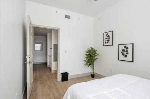 een witte slaapkamer met een bed en een potplant bij 4B 3BA Premium Family Apartment with Gym in Charlotte