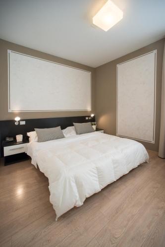 a large white bed in a bedroom with a large window at Berghotel in Bergamo