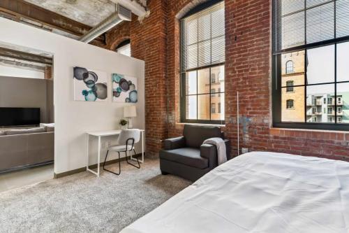 a bedroom with a brick wall and a bed and a couch at 2BR 2BA Lux Historic Loft With Pool in Pittsburgh
