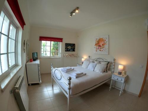 a bedroom with a large white bed with two windows at Luxury Apartment 4 Bedrooms Pool in Marisol in Corroios