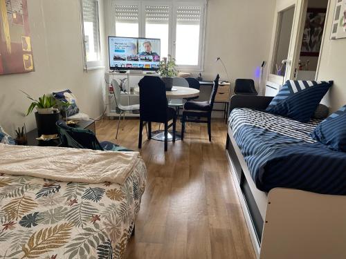 Cette chambre comprend 2 lits, une table et une télévision. dans l'établissement Manue studio 200 m centre au calme, à Vesoul