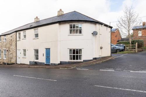 una casa blanca con una puerta azul en una calle en Retreat in Axminster: Your Getaway near Devon en Axminster