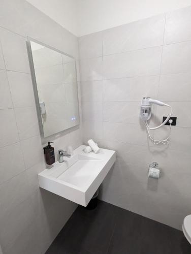 a white bathroom with a sink and a mirror at Hotel Carignano in Lucca