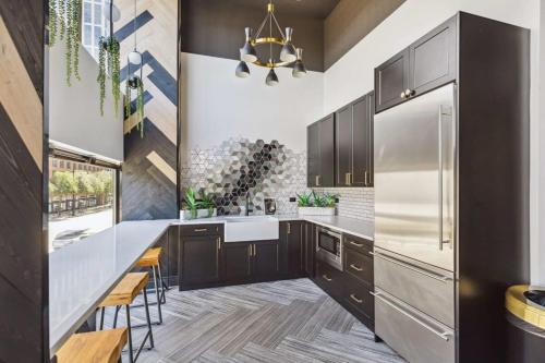a kitchen with black cabinets and a stainless steel refrigerator at 2BR Modern South Loop Suite With Views & Gym in Chicago