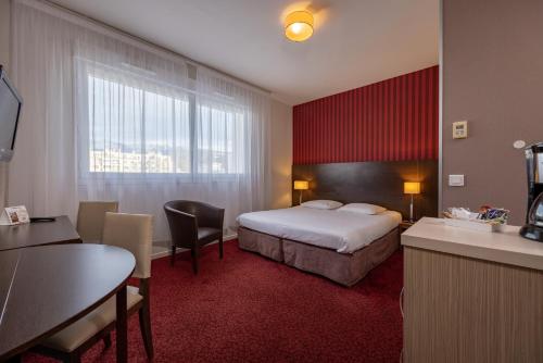 Habitación de hotel con cama, mesa y sillas en The Originals Residence KOSY appart'hôtels - Les Cèdres, en Grenoble