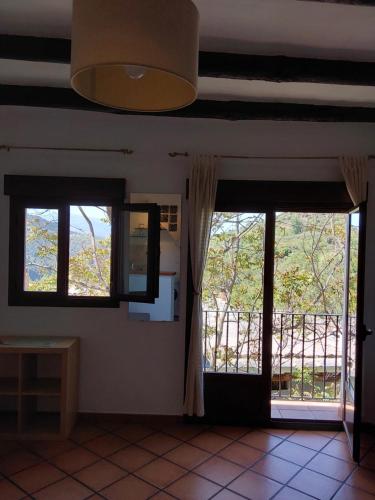 Habitación con 2 ventanas y vistas a un balcón. en Valle de la Calma - Apartamentos rurales de Mecina, en Granada