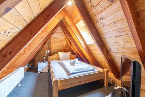 um quarto com uma cama num sótão de madeira em Ferienwohnung-J-Jacobs em Wrixum