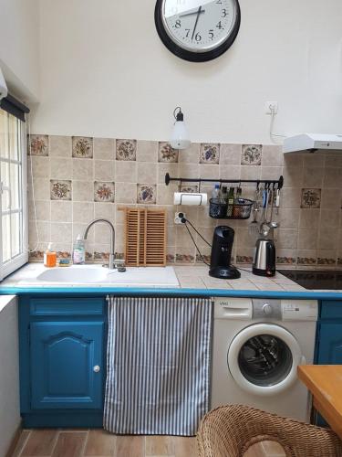 une cuisine avec une machine à laver et une horloge au mur dans l'établissement La cabane du Petit Matelot, à Honfleur