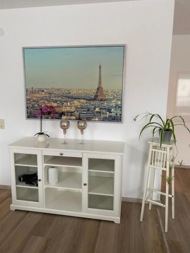 a white cabinet in a room with a picture of the eiffel tower at Zimmervermietung Mauersberger in Wendeburg