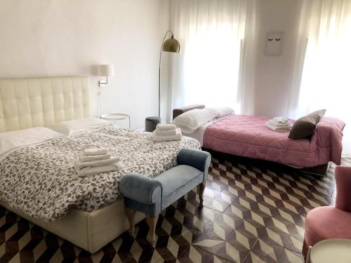 a bedroom with two beds and a chair with towels at Allegra Toscana - Affittacamere Guest house Arezzo in Arezzo