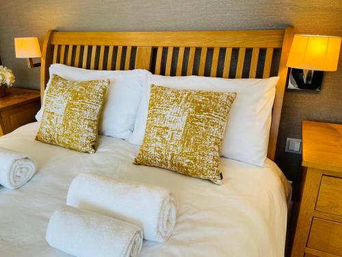 a bed with white and gold pillows on it at Luxury Stay in Orpington
