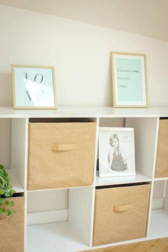 a white shelf with two pictures and two boxes at Le douillet : Duplex élégant en Centre ville in Albertville