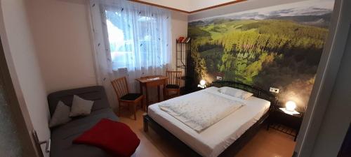 een slaapkamer met een bed en een stoel en een schilderij bij Haus Bührer in Freiamt