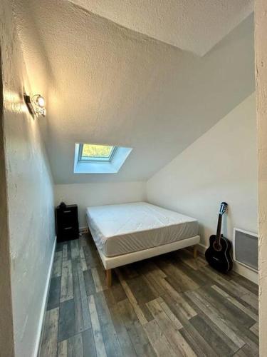Un dormitorio con una cama y una guitarra. en Au coeur du village T2 tout neuf climatisé, en Pierrefeu-du-Var