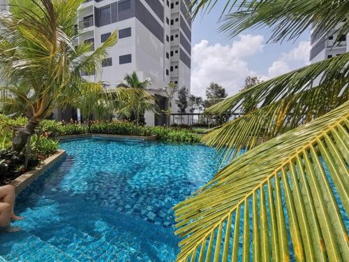 una piscina con una palmera y un edificio en Traders Garden Cozy 2 BR Family Suite with WiFi Netflix, en Cheras