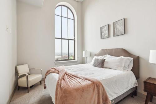 a bedroom with a bed and a chair and a window at 2BR Luxury Apartment Rooftop Pool & Gym in Baltimore