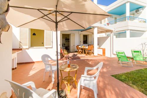 eine Terrasse mit Tisch und Stühlen und einem Sonnenschirm in der Unterkunft Villetta Relax With Pool in Residence - Happy Rentals in Melendugno